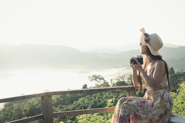 Une femme avec un appareil photo pour voir la vue sur la montagne