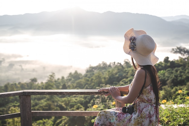 Photo gratuite une femme avec un appareil photo pour voir la vue sur la montagne