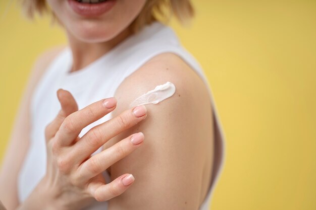 Femme appliquant une lotion sur l'épaule