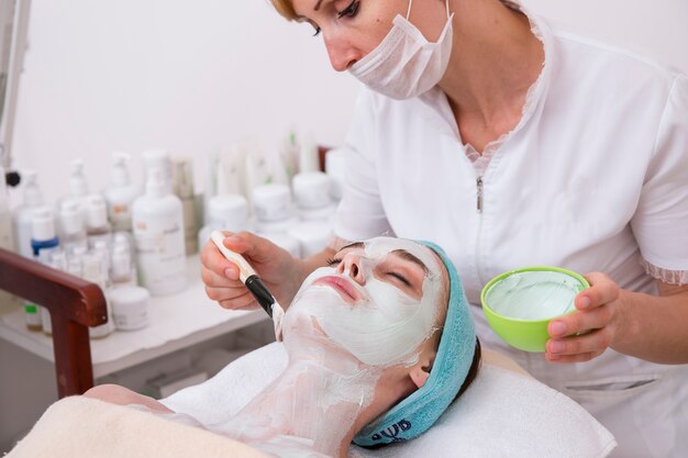 Femme appliquant un masque à un client