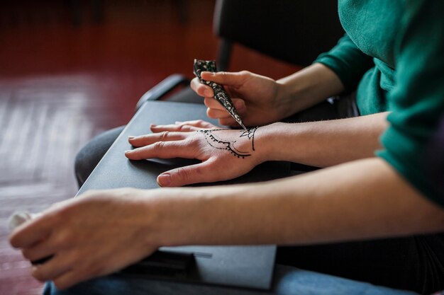 Une femme appliquant un tatouage mehndi sur la main de la femme