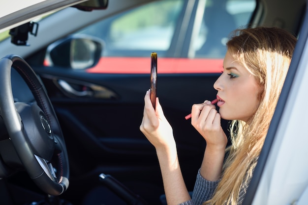 Femme d&#39;appliquer le maquillage dans la voiture