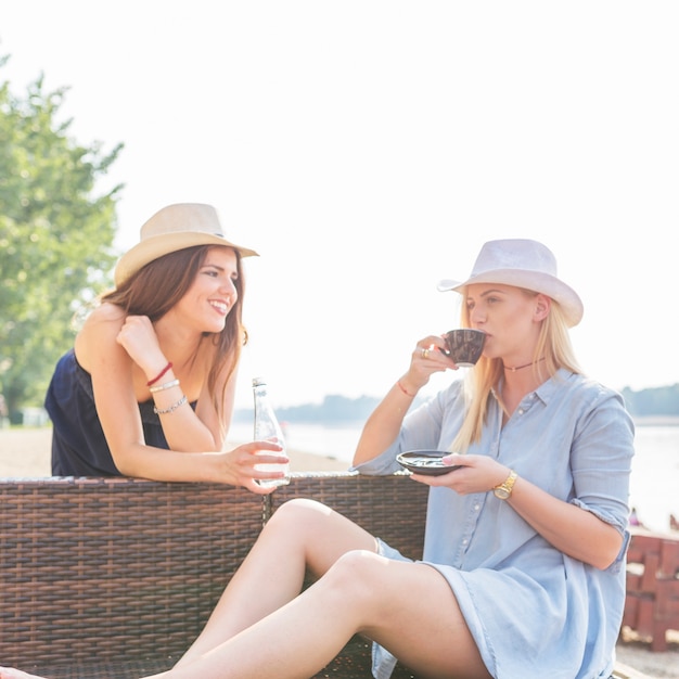 Femme appréciant le café avec des amies appréciant à la plage