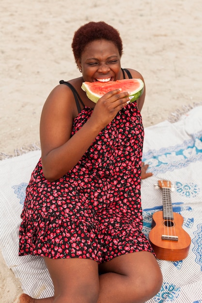 Femme appréciant la pastèque à la plage