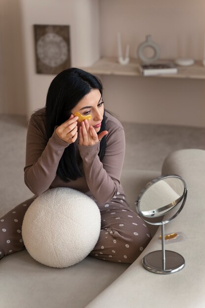 Femme appréciant sa routine beauté avec des pansements oculaires dorés