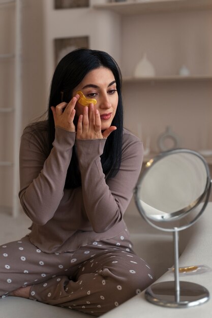 Femme appréciant sa routine beauté avec des pansements oculaires dorés