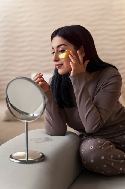 Femme appréciant sa routine beauté avec des pansements oculaires dorés