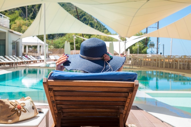 Femme appréciant et se détendre sur une chaise longue au bord de la piscine