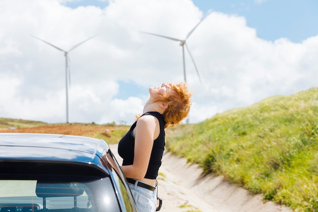 Femme appréciant le soleil par la fenêtre de la voiture par temps clair