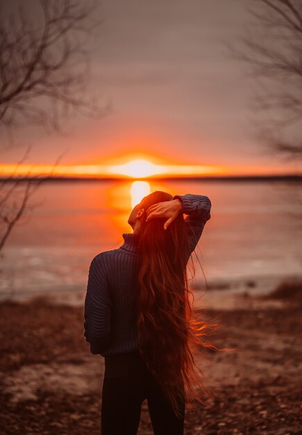 Femme appréciant le temps de détente au bord du magnifique lac au lever du soleil