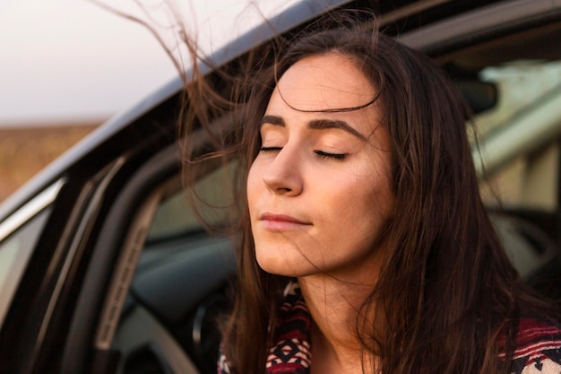 Femme appréciant le vent de son siège auto à l'extérieur