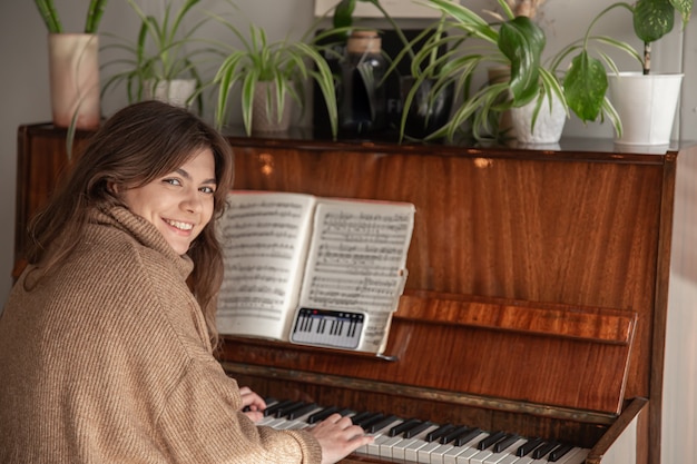 Une femme apprend à jouer du piano en utilisant le téléphone, un cours de musique, une formation en ligne.