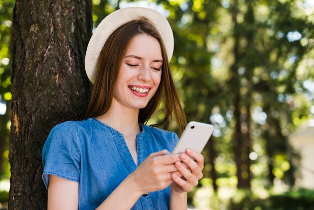 Femme appuyée contre un arbre