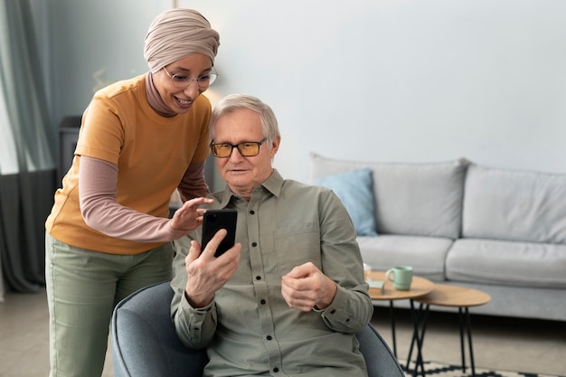 Photo gratuite femme arabe apprenant à un homme âgé à utiliser un smartphone