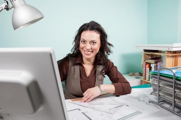 Femme architecte souriante à sa table travaillant sur des plans. Affaires et créativité. Travail d'architecte