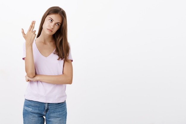 Femme arrogante dérangée mourant d'ennui agissant immature montrant le geste du pistolet à doigt près des tempes et inclinant la tête au roulement des yeux