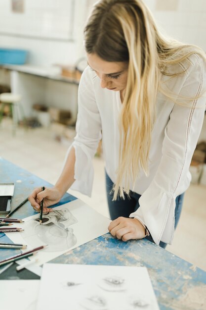 Femme artiste esquissant le squelette sur papier avec un crayon sur l&#39;établi