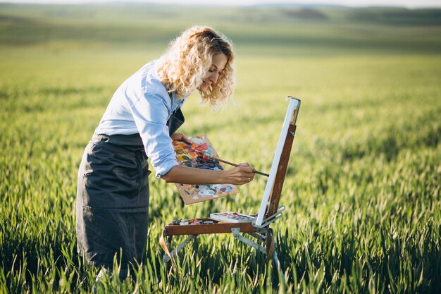 Femme artiste peinture avec des peintures à l&#39;huile dans un champ