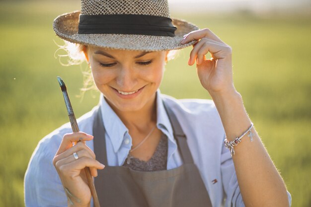 Femme artiste peinture avec des peintures à l&#39;huile dans un champ