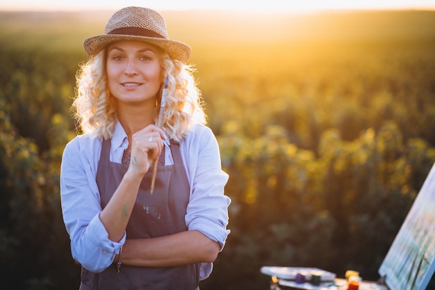 Femme artiste peinture avec des peintures à l&#39;huile dans un champ