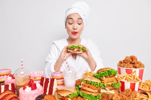 Une Femme Asiatique Affamée Lèche Les Lèvres Peintes En Rouge Regarde Un Délicieux Hamburger Choisit Un Délicieux Régime De Pause Collation