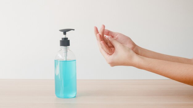 Femme asiatique à l'aide de gel d'alcool désinfectant pour les mains se laver les mains pour protéger le coronavirus. La femme pousse la bouteille d'alcool pour nettoyer les mains pour l'hygiène lorsque la distance sociale reste à la maison et le temps de quarantaine.