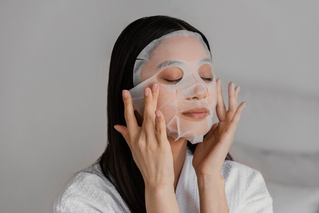 Femme asiatique à l'aide d'un masque en feuille