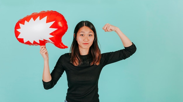 Femme asiatique avec ballon de discours montrant les muscles