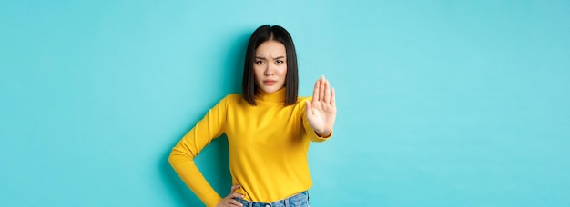 Photo gratuite une femme asiatique confiante et sérieuse ne dit pas de geste d'arrêt pour interdire et avertir qu'elle n'est pas d'accord avec ainsi