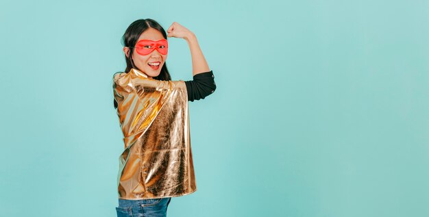 Femme asiatique en costume de super-héros montrant des muscles