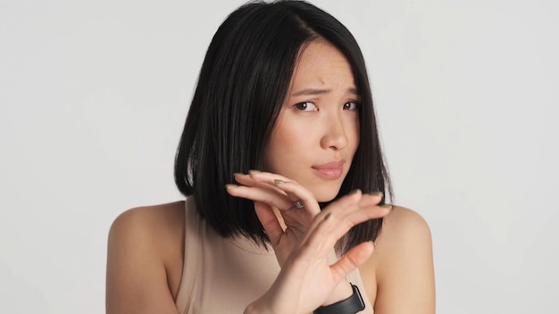 Femme asiatique effrayée se cachant le visage avec les mains effrayées par quelque chose sur fond blanc Humain et phobie