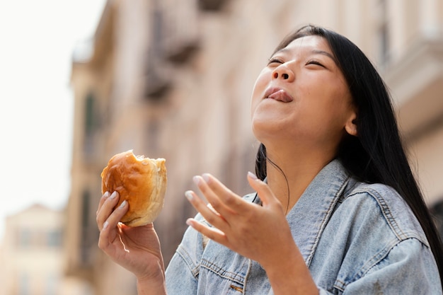 Femme asiatique étant heureuse après avoir acheté de la nourriture de rue