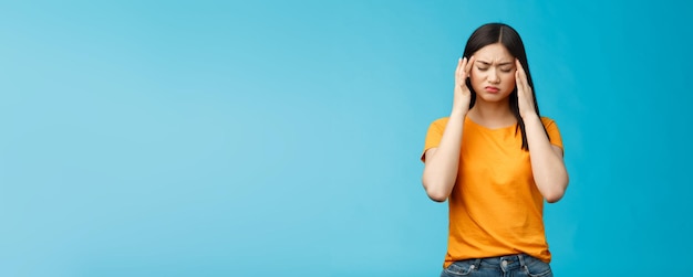 Femme asiatique fatiguée en détresse, coupe de cheveux sombre, toucher les temples, souffrir d'une énorme migraine, avoir besoin d'analgésiques