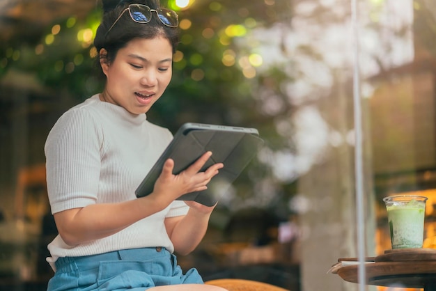 Femme asiatique freelance numérique nomade carrière bonheur travail joyeux souriant travaillant en ligne avec un appareil intelligent tablette smartphone à l'étranger occupation projet travailler n'importe où nouveau style de vie sans cadre