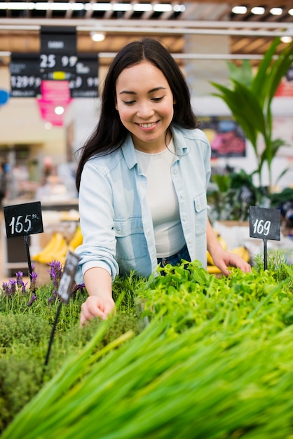 Femme asiatique joyeuse, cueillette de verdure à l'épicerie