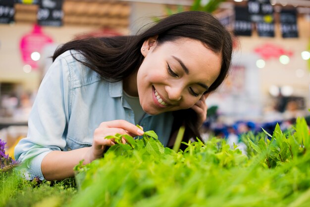 Femme asiatique joyeuse, sentant la verdure dans une épicerie