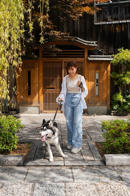 Photo gratuite femme asiatique promenant son chien husky à l'extérieur