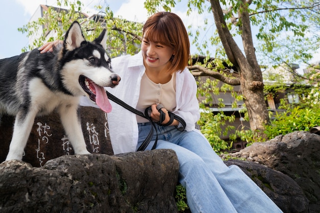 Photo gratuite femme asiatique promenant son chien husky à l'extérieur