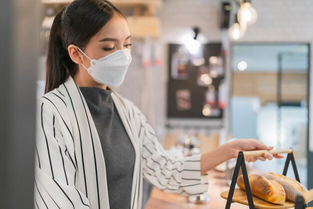 Une femme asiatique, propriétaire d'un café, prépare un panier à pain de boulangerie avant l'ouverture du magasin