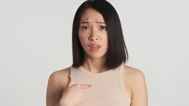 Femme asiatique à la recherche d'indignation indiquant elle-même isolé sur fond blanc Expression mécontente