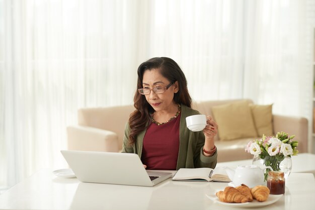 Femme asiatique, regarder, quelque chose, sur, ordinateur portable, matin