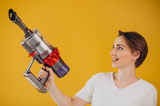 Femme avec aspirateur accumulateur sur fond jaune