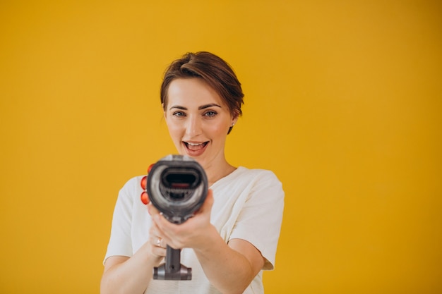 Femme avec aspirateur accumulateur sur fond jaune