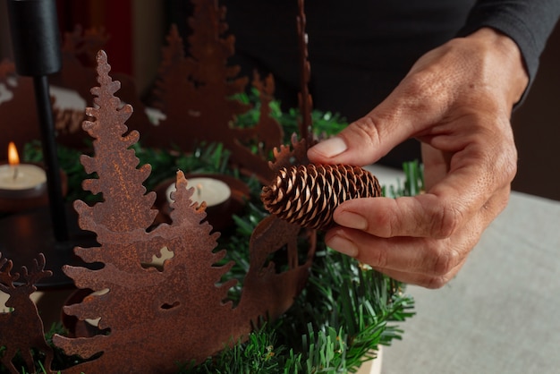 Une femme assemblant une couronne sur le thème des fêtes