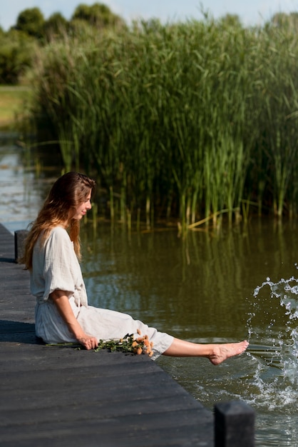 Femme assise au bord du lac plein coup