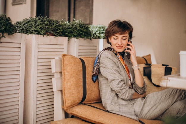 Photo gratuite femme assise au café et à l'aide de téléphone