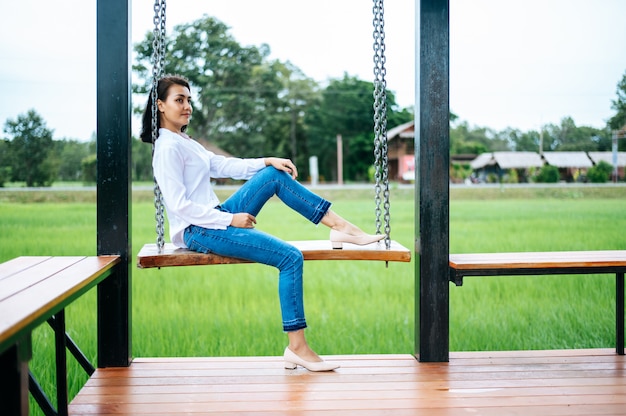 femme assise sur la balançoire et posa ses mains sur ses genoux