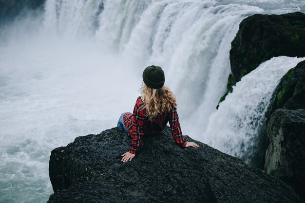 Femme assise sur le bord de la falaise sur la cascade