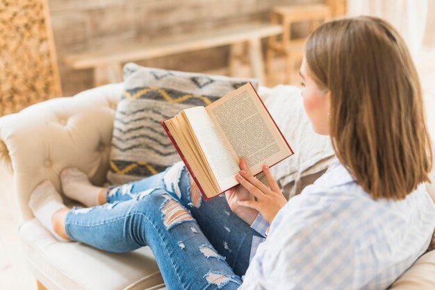 Femme assise sur canapé avec livre de lecture