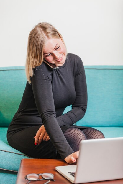 Femme assise sur le canapé parlant au téléphone